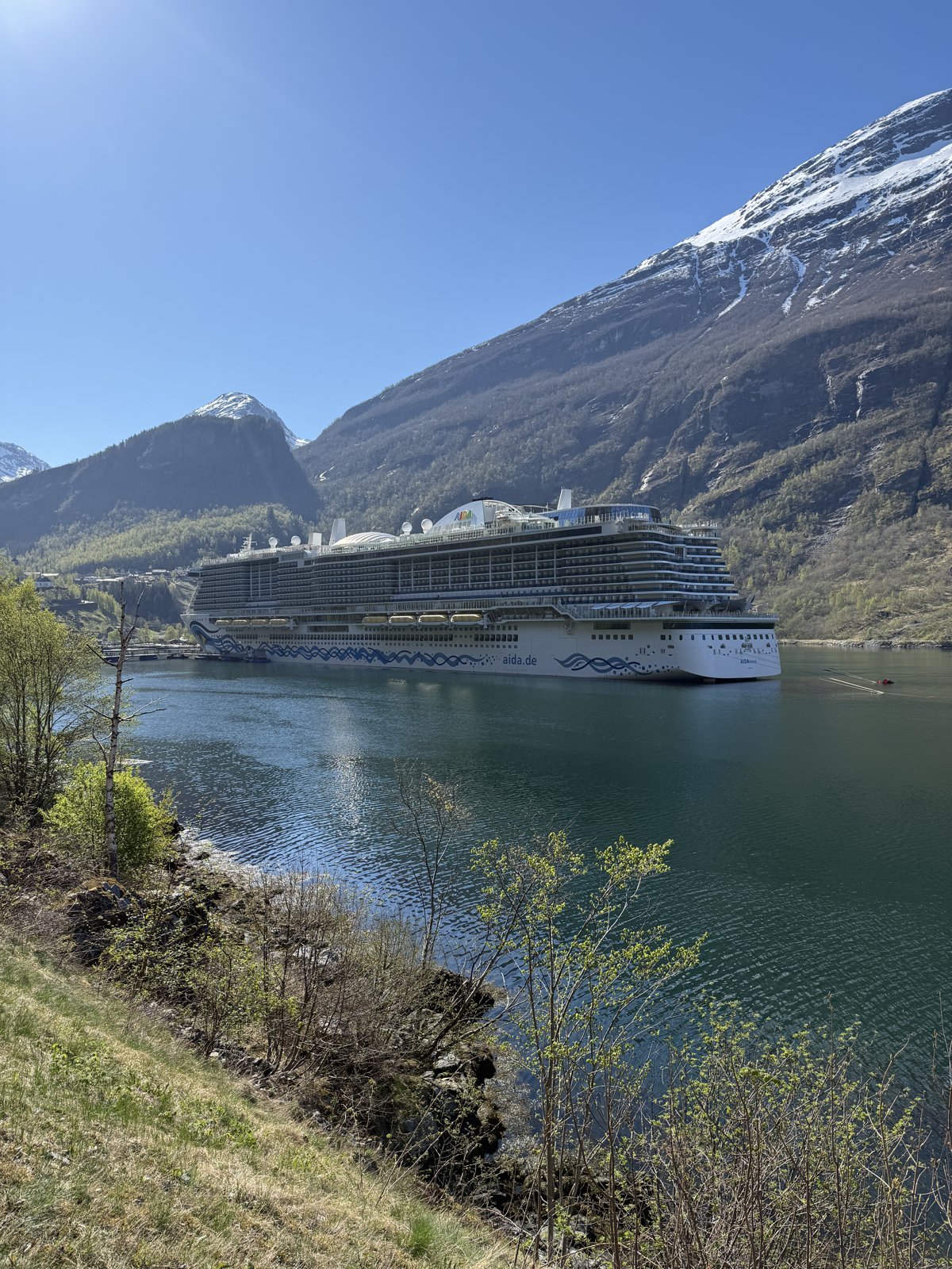 Die AIDA Nova liegt im Geirangerfjord vor schneebedeckten Bergen